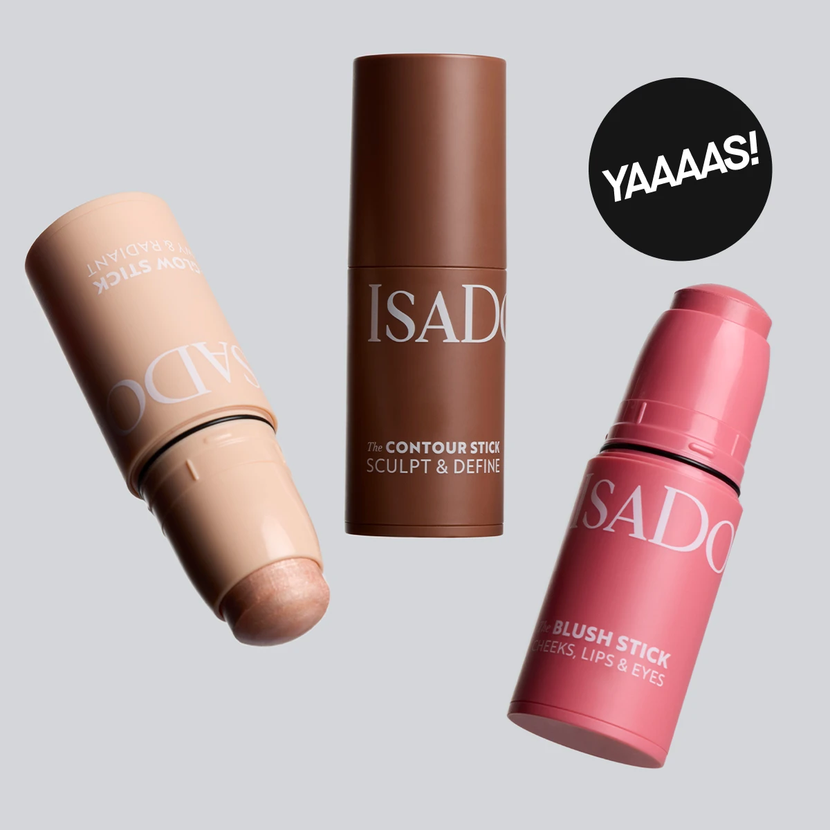IsaDora-meikkipuikot vaalealla taustalla: contour stick, glow stick ja blush stick eri sävyissä sekä ”YAAAS!”-merkintä.