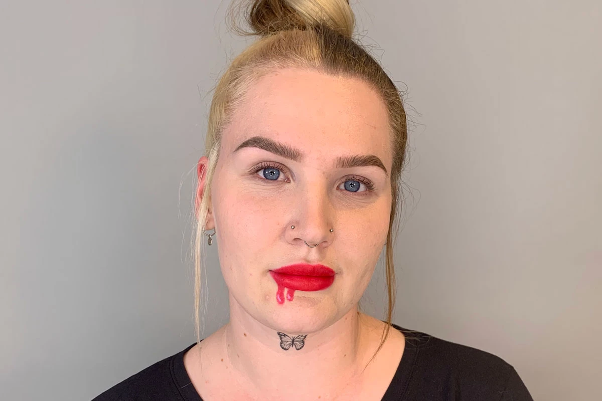 Personen har ljusröda läppar med en blodig urladdning ritad på dem.