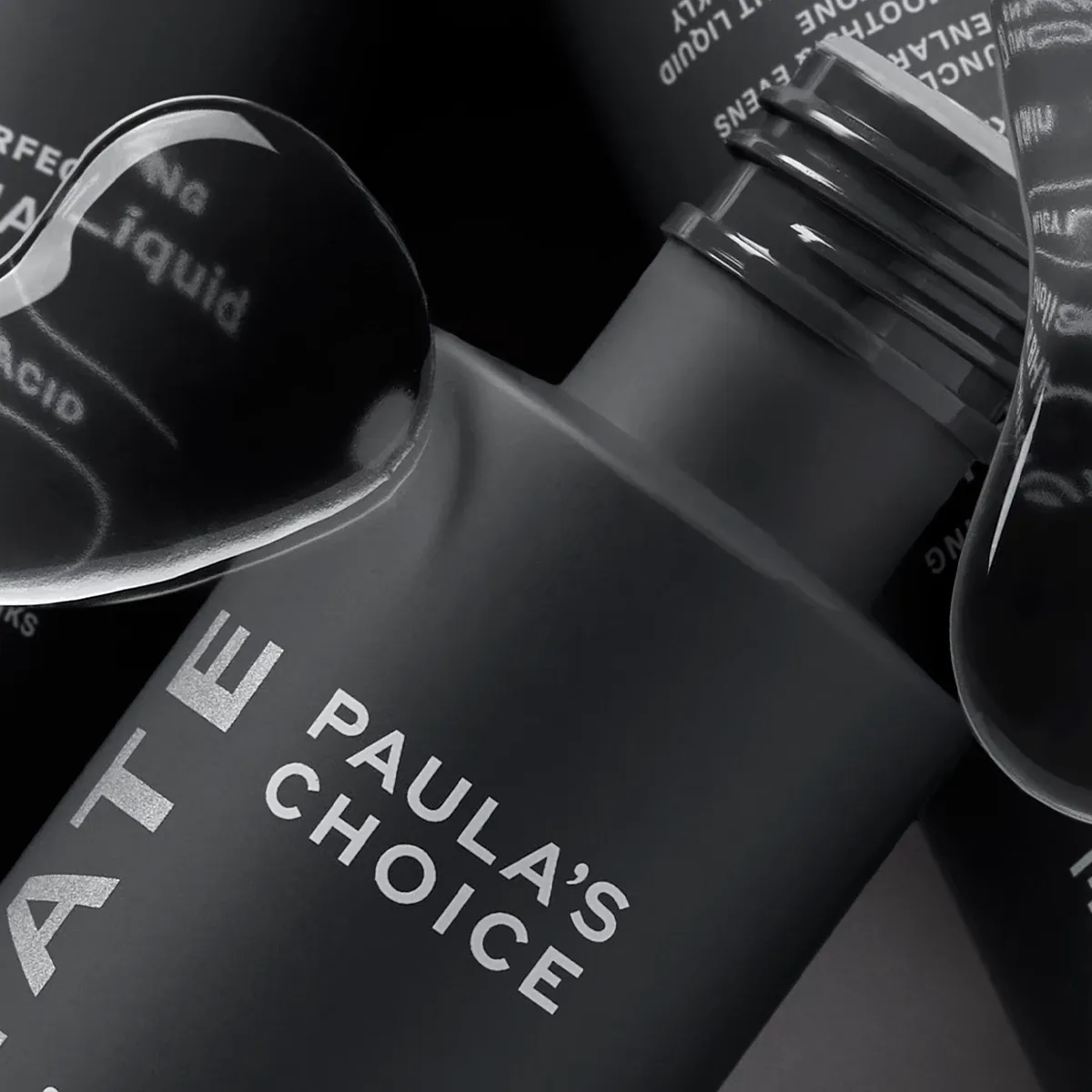 Kolme Paula's Choice -tuotetta lähikuvassa harmaalla taustalla ja vesipisaroita etualalla.