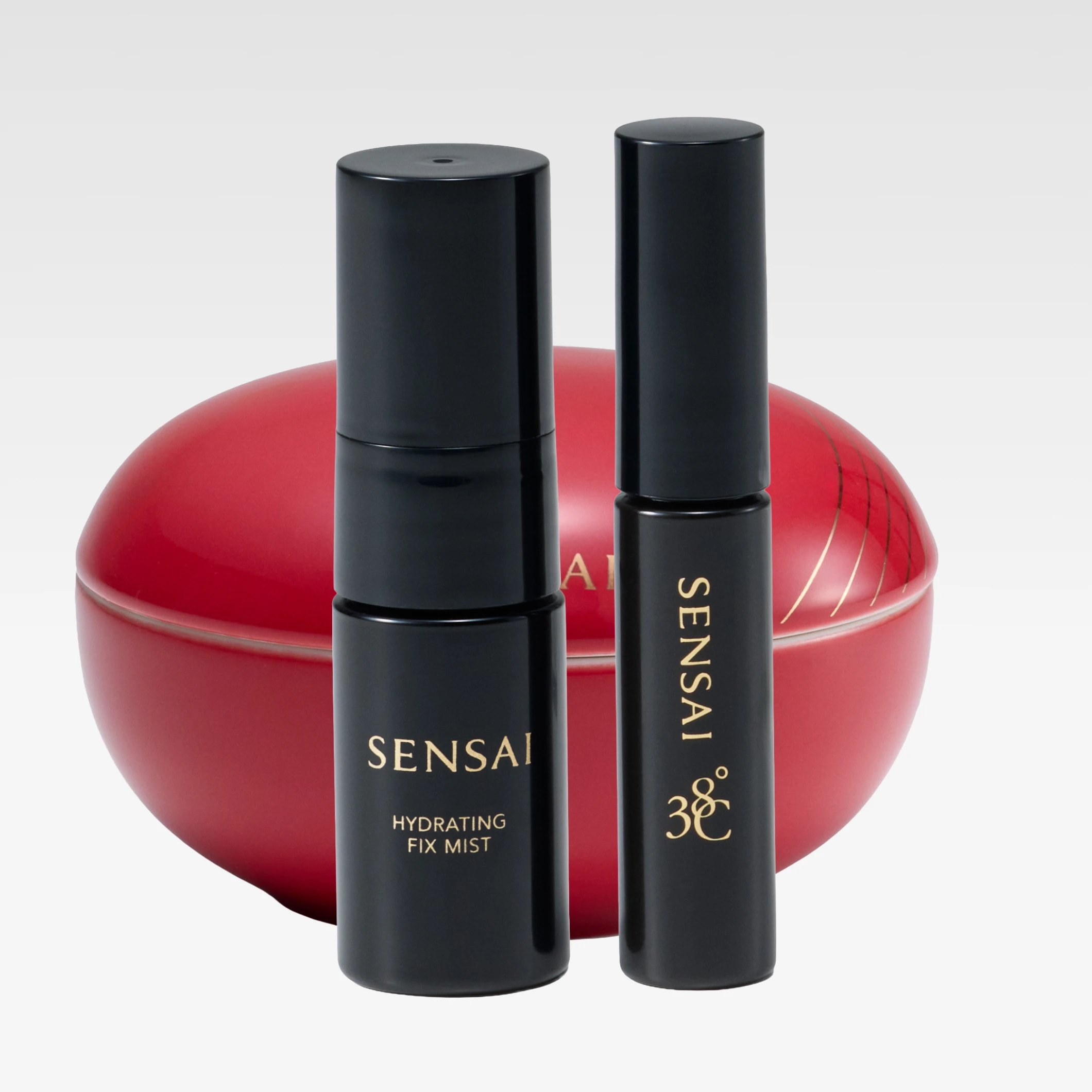 Sensai makeup og hudpleie i svarte emballasjer med teksten "SENSAI" foran en rød rund boks.