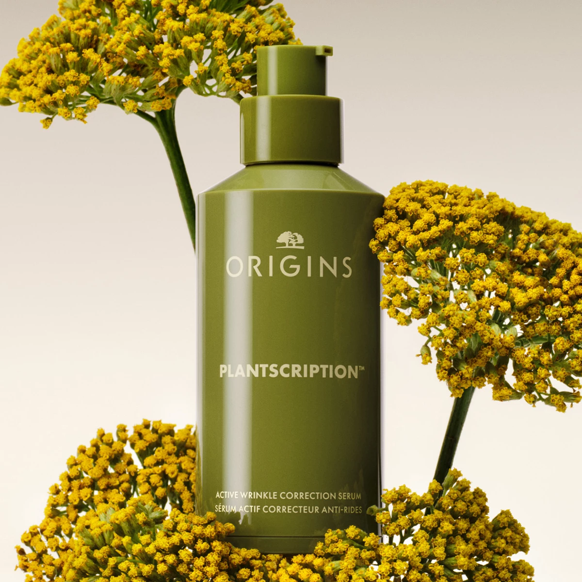 Origins Plantscription Active Wrinkle Correction Serum ympäröitynä keltaisilla kukilla vaaleaa taustaa vasten.