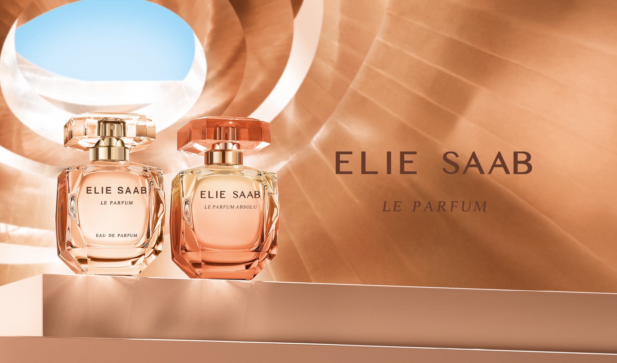 Två Elie Saab parfymflaskor, Le Parfum och Le Parfum Absolu, stilfullt uppställda. Bakgrunden har ett ljust, geometriskt mönster.