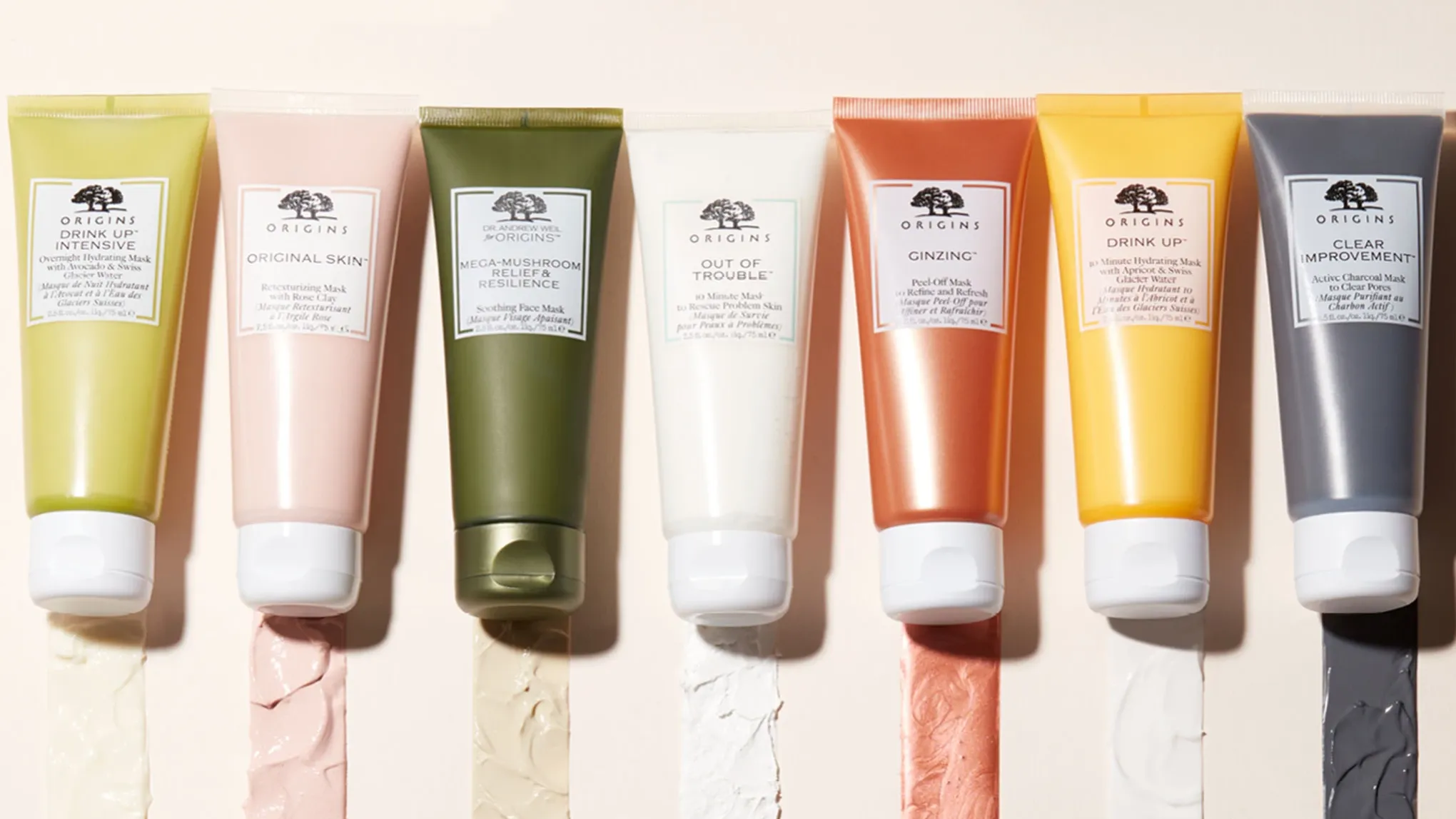 Produkter fra Origins med innholdet spredt under, mot en beige bakgrunn i sollys.