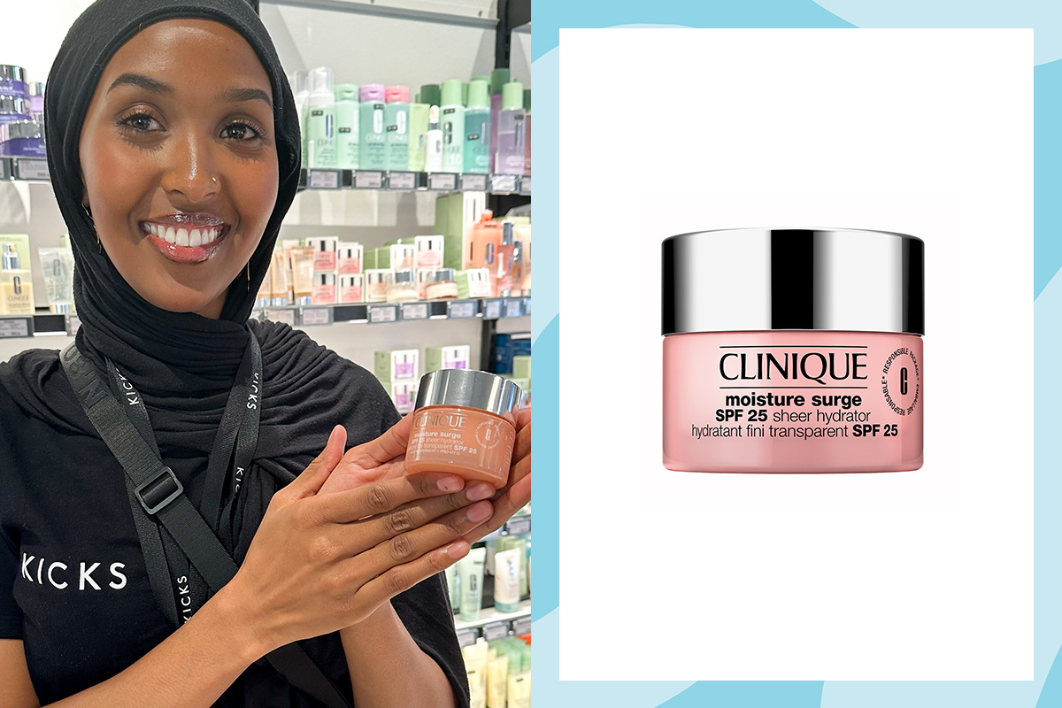Hymyilevä KICKS-työntekijä pitää käsissään Clinique Moisture Surge SPF 25 -voidetta myymäläympäristössä.