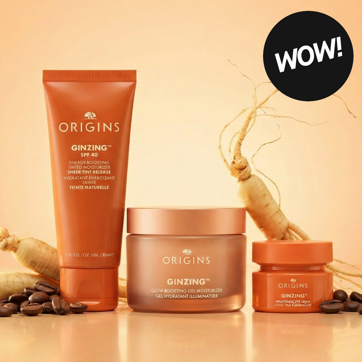 Hudpleieprodukter fra Origins med teksten “ORIGINS GINZING SPF 40 Energy-Boosting Tinted Moisturizer Sheer Tint Release”, “GINZING Glow-Boosting Gel Moisturizer” og “GINZING Refreshing Eye Cream to Brighten and Depuff”. Produktene står sammen med kaffebønner og ginsengrot samt en rund etikett med teksten “WOW!”.