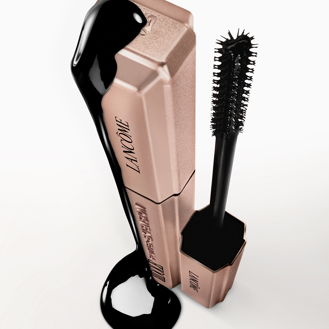 Nærbilde av en person som påfører Lancôme mascara på øvre vipper, med tydelig børste og åpnet hylse nær øyet.