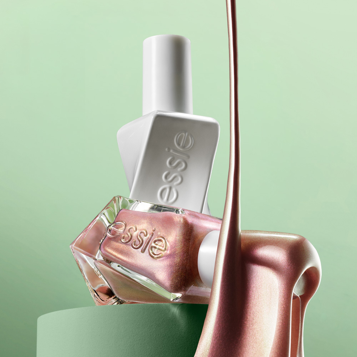 Essie nagellack i metalliskt rosa nyans mot grön bakgrund; lack rinner ner bredvid flaskan.