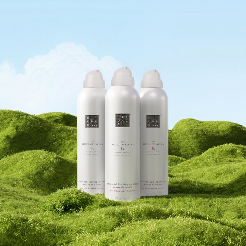 Tre Rituals The Ritual of Sakura dusjgeléflasker på grønt gress med blå himmel i bakgrunnen.