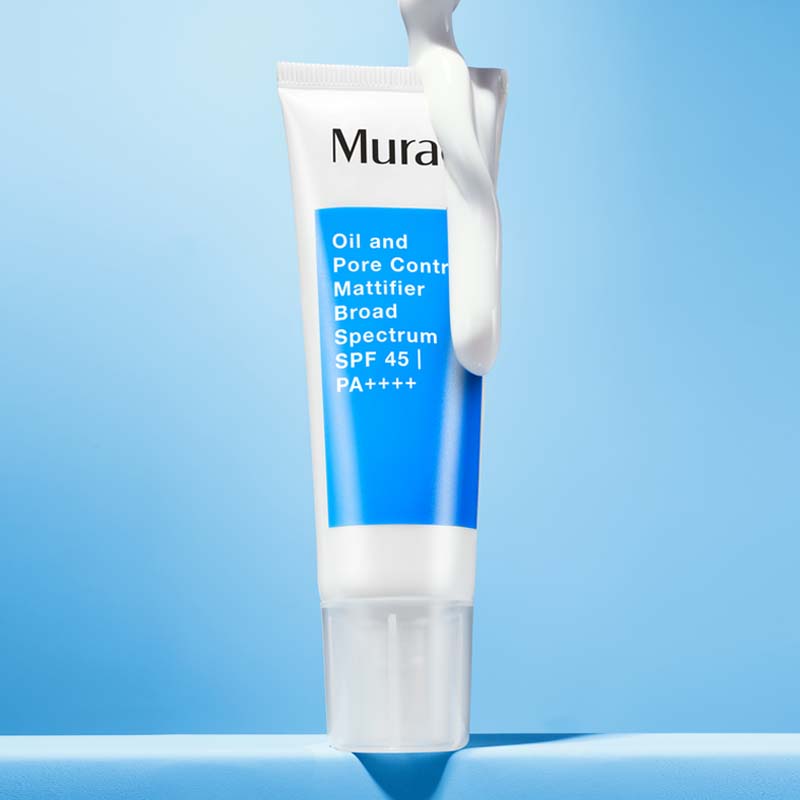 Ansiktskrem fra Murad plassert mot en lyseblå bakgrunn. Tuben er hvit med en blå etikett som viser produktnavnet. På toppen av tuben er det påført en hvit krem som fremhever produktets tekstur og solbeskyttende egenskaper.
