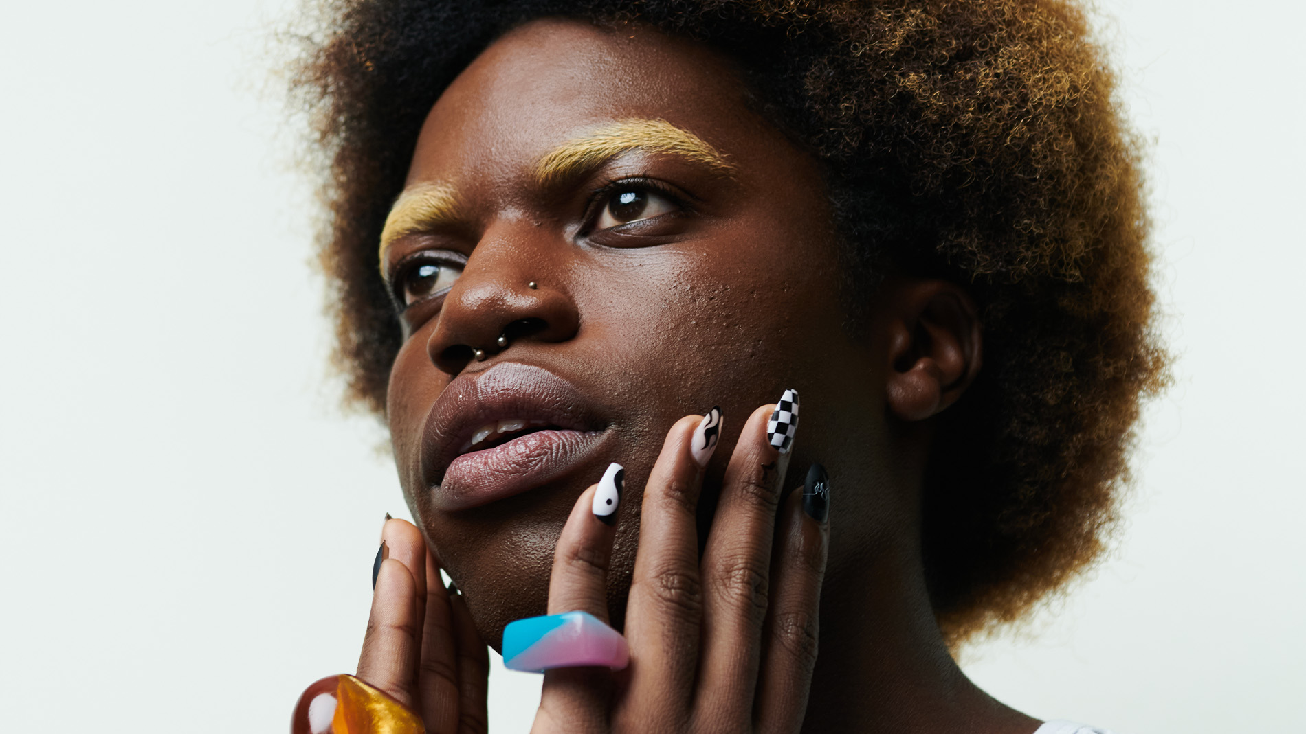 Person med afrofrisyre og fargerike ringer på fingrene.