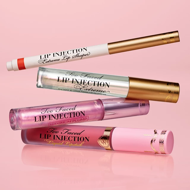 Fire leppeprodukter fra Too Faced er stablet mot en rosa bakgrunn. Fra øverst til nederst: en blyant i hvitt og gull, en gjennomsiktig tube og to rosa tuber.