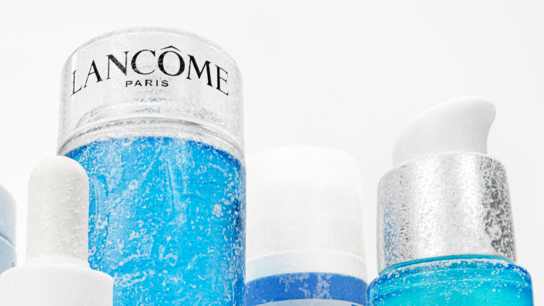 Produkt av Lancome underifrån tillsammans med andra produkter, mot en vit bakgrund