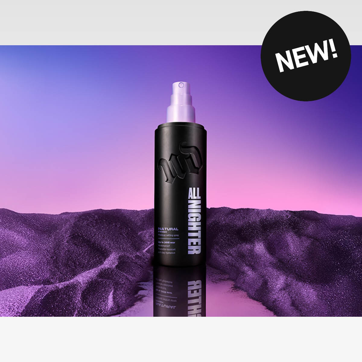 Musta Urban Decay All Nighter -meikinkiinnityssuihke violetinsävyisessä maisemassa; oikeassa yläkulmassa teksti “NEW!”.