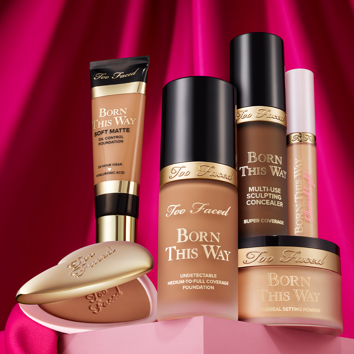 Basemakeup fra Too Faced står på en rosa pall med mørkere rosa bakgrunn.