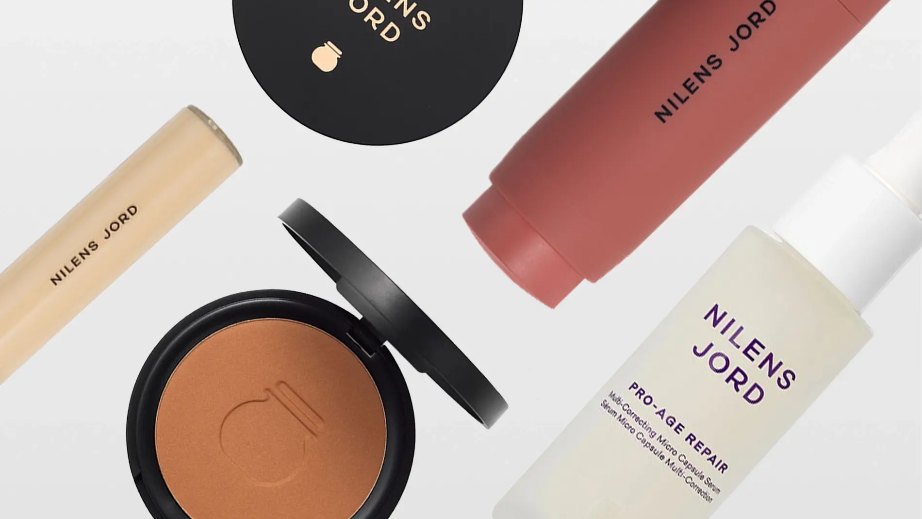 En samling av Nilens Jord skönhetsprodukter, inklusive en concealer, ett kompaktpuder, en ansiktskräm och en ansiktsserum. Produkterna är stilfullt arrangerade mot en vit bakgrund.