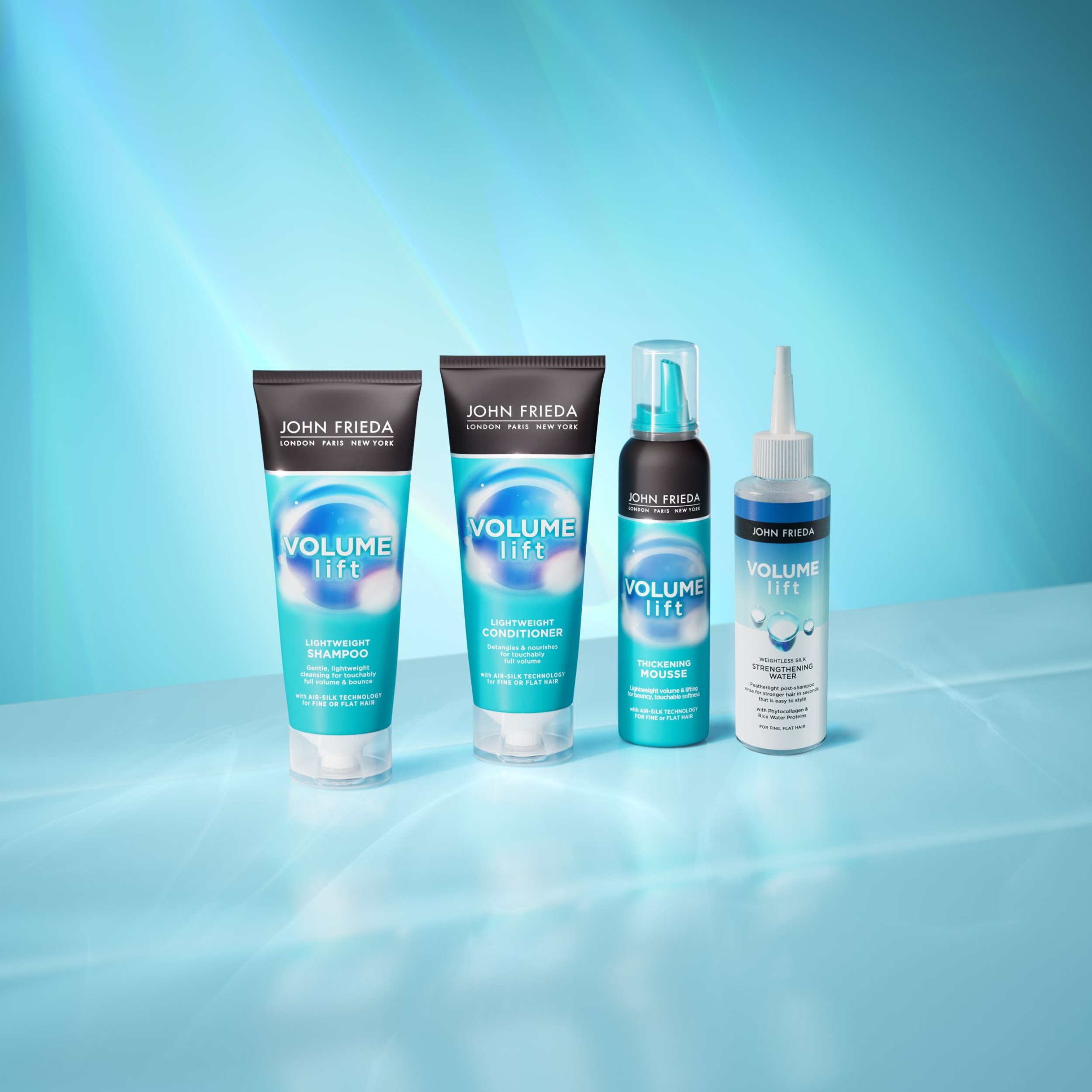 Neljä John Frieda Volume Lift -tuotetta vaaleansinisen taustan edessä. Kuvassa on shampoo, hoitoaine, paksuntava vaahto ja muotoilusuihke.