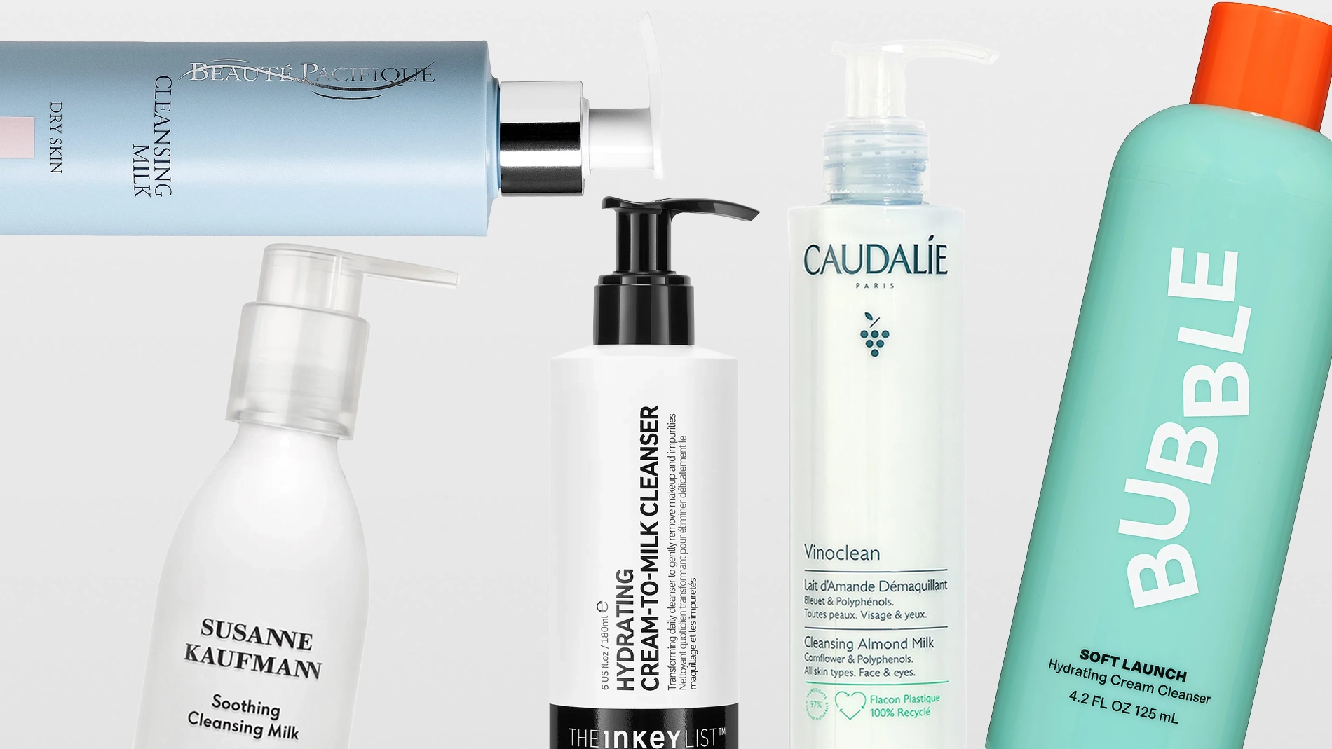 Flere hudpleieprodukter i form av rensemelk fra blant annet Susanne Kaufmann, The Inkey List, Caudalie og Bubble skincare, med pumpeflasker og tuber mot en lys bakgrunn. Synlig tekst inkluderer “Soothing Cleansing Milk”, “Oat Cleansing Balm”, “Vinoclean Cleansing Almond Milk” og “Milky Silky Calming Cleansing Lotion”.