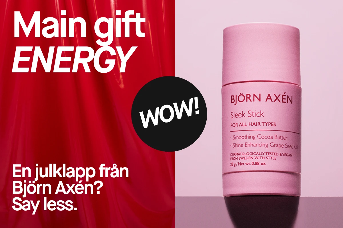 Reklambild med Björn Axén Sleek Stick i rosa design på ljusrosa bakgrund. Till vänster syns texten “Main gift energy – En julklapp från Björn Axén? Say less.” i vit och röd layout, vilket skapar en modern och trendig julkänsla.