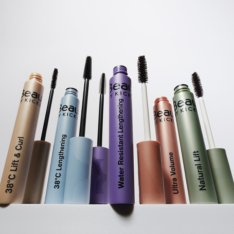 Erilaisia BeautyAct by KICKS -ripsivärejä, kuten 38°C Lift & Curl, 38°C Lengthening, Water Resistant Lengthening, Ultra Volume ja Natural Lift. Ripsiväripakkauksissa on eri värejä: beige, sininen, violetti, oranssi ja vihreä. Tausta on valkoinen.