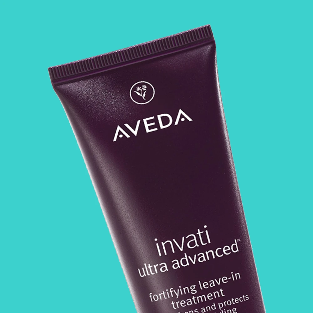 Aveda Invati Ultra Advanced -vahvistava jätettävä hoitoaine. Tumma violetti tuubi turkoosilla taustalla.