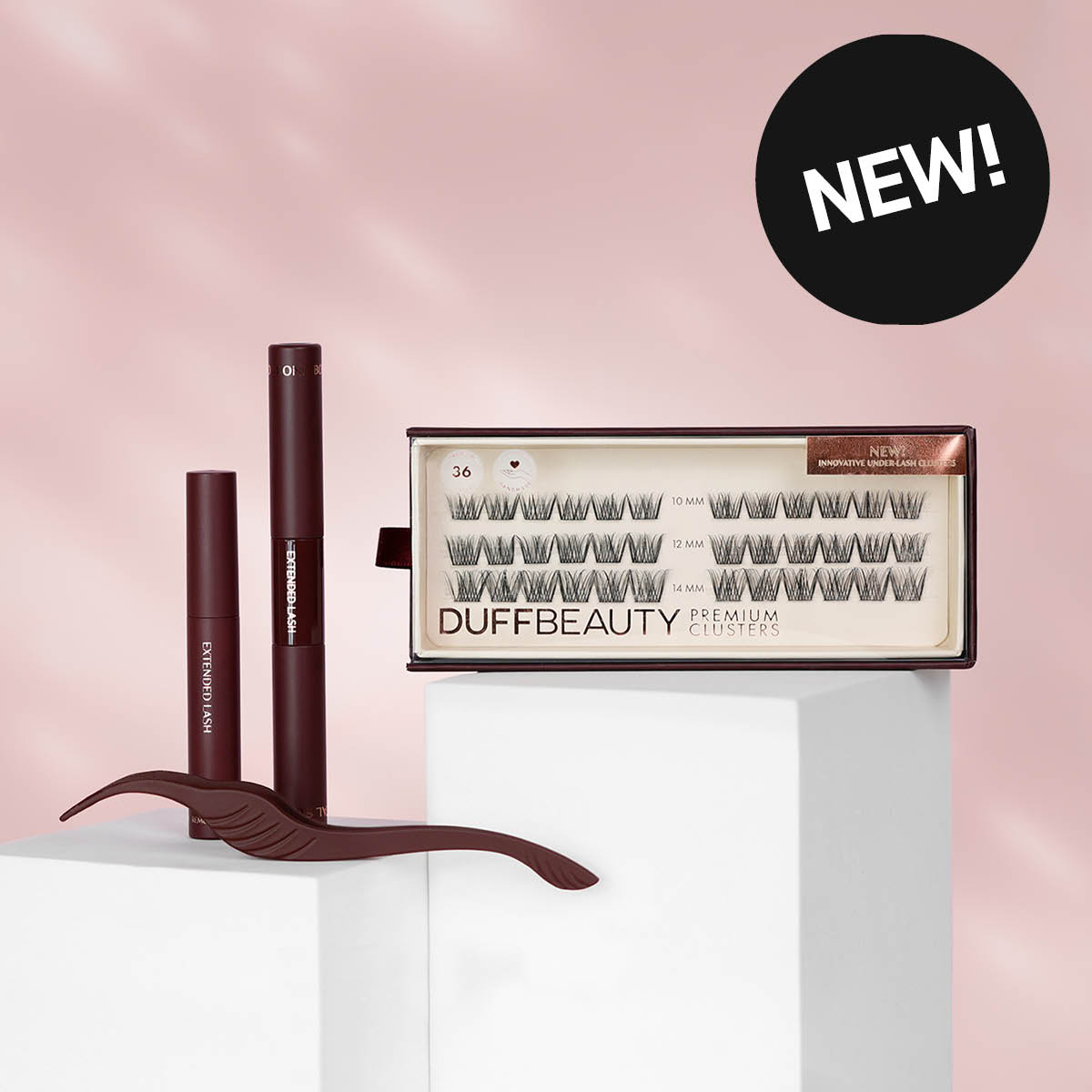 To Duff Beauty-øyenprodukter på hvite podier mot rosa bakgrunn. Svart sticker med teksten "NEW".