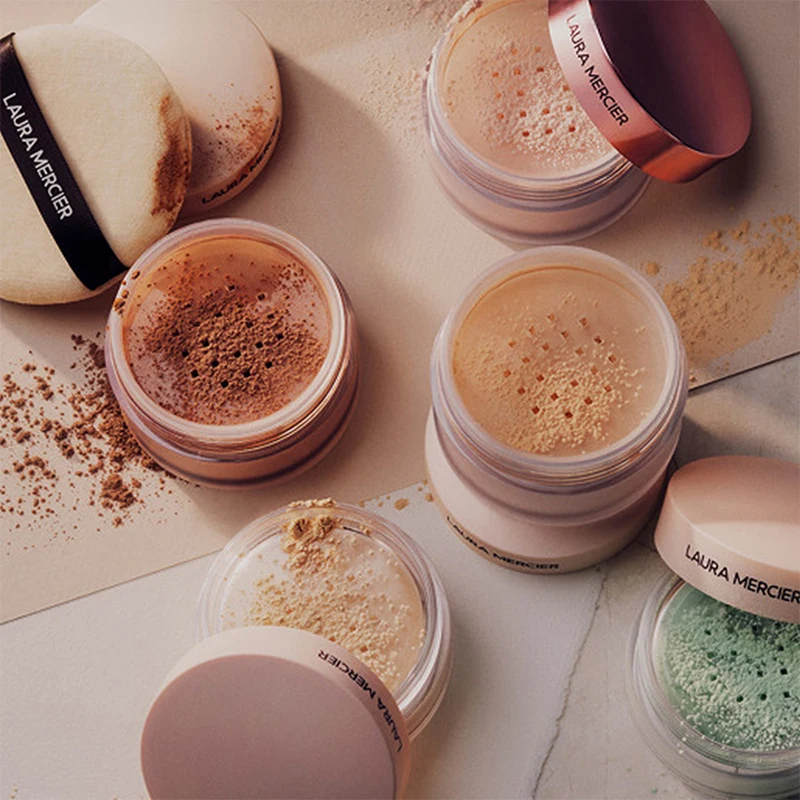 Laura Mercier lösa puder i olika nyanser, med två puderpuffar och spillt puder.