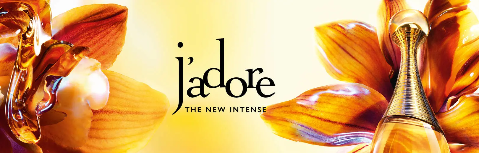 Gyllen J'adore THE NEW INTENSE parfymeflaske blant oransje blomsterblader med glinsende væskedråper.