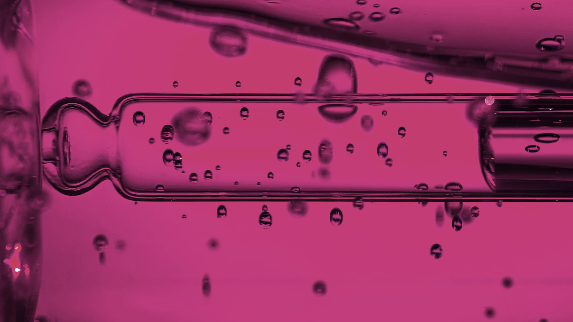 Närbild av pipett och rosa vätskedroppar.