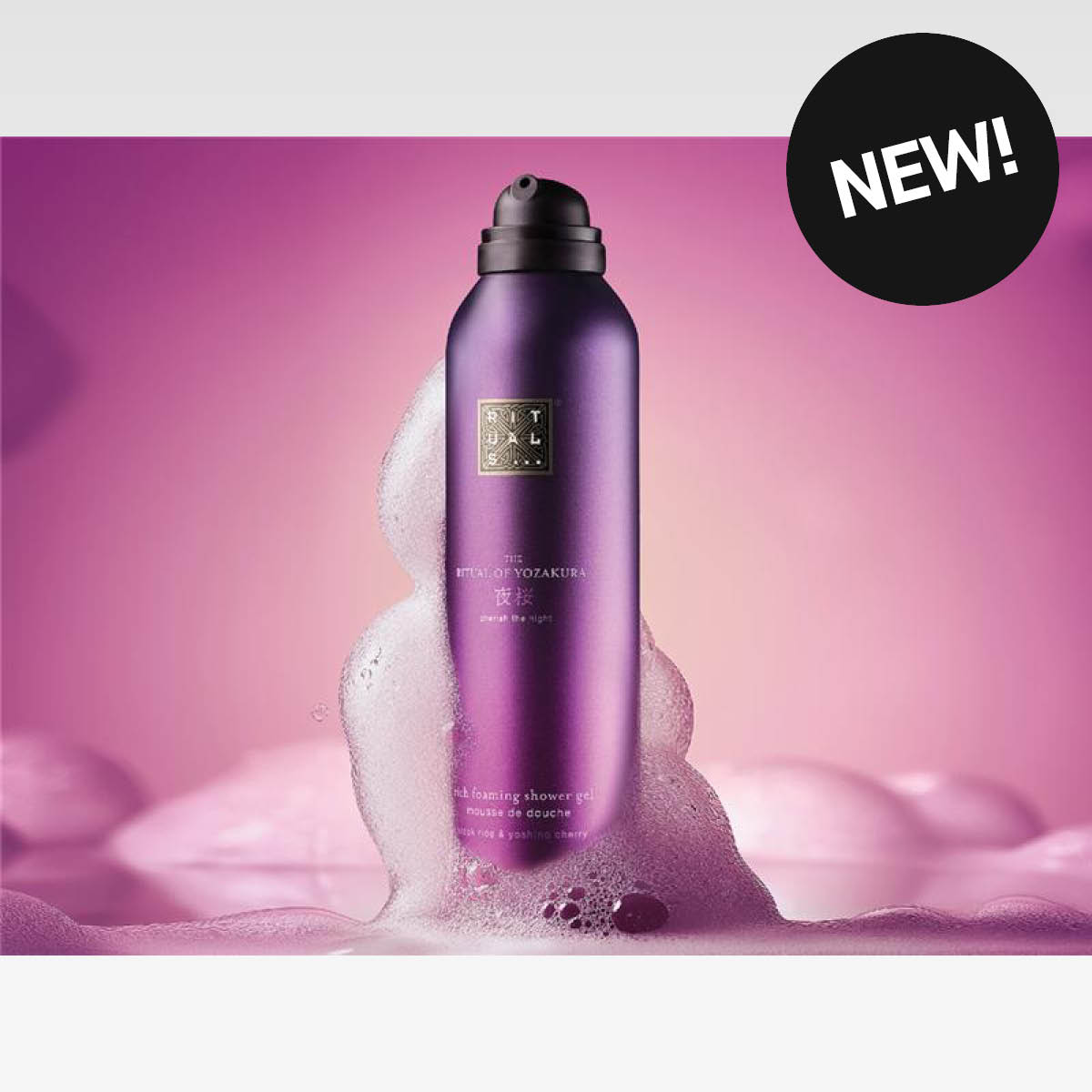 Lila Rituals-duschgelflaska omgiven av rosa skum. I bildens övre hörn syns en svart cirkel med texten ”NEW!”.