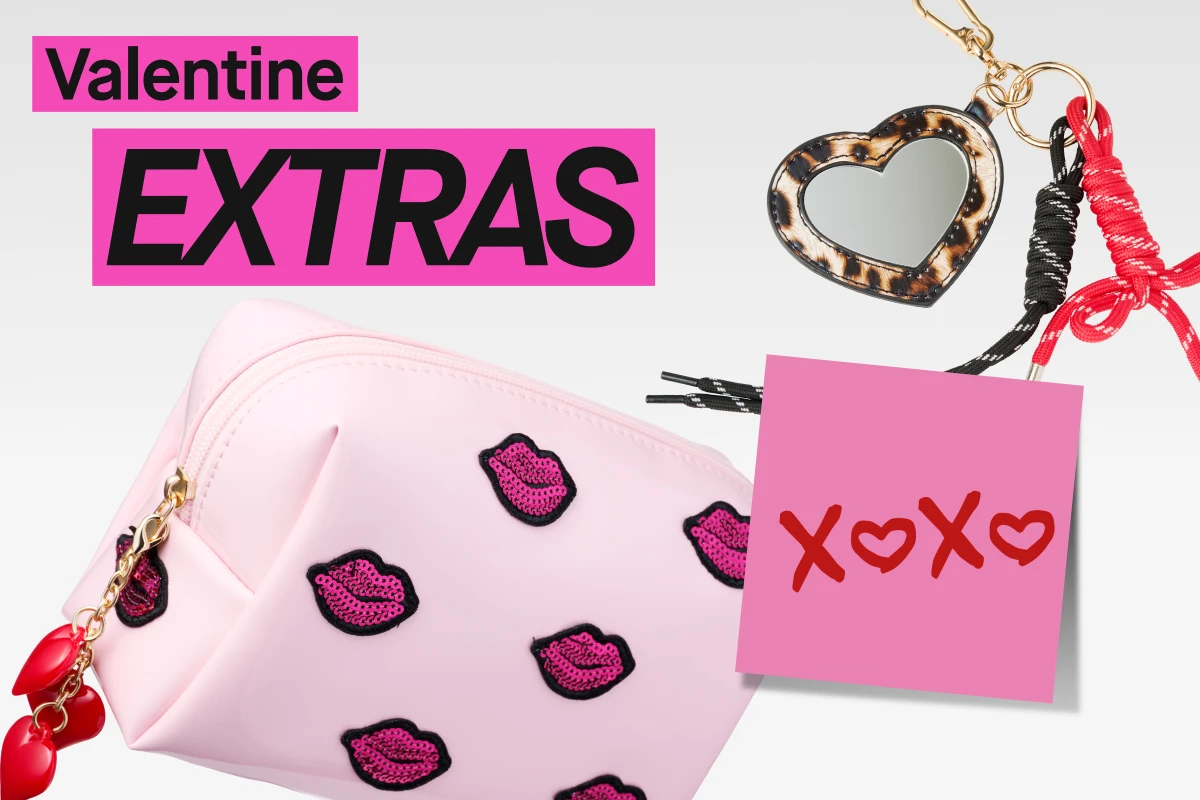 Vaaleanpunainen meikkipussi huulikuvioilla valkoisella taustalla. Kuvassa on teksti “Valentine EXTRAS”, vaaleanpunainen muistilappu tekstillä “XOXO”, sydämenmuotoinen avaimenperä peilillä, punamusta nauha ja vaaleanpunainen hiusklipsi.