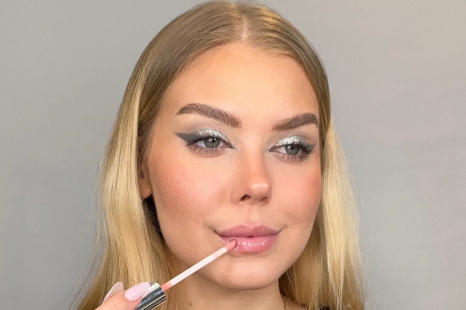 Kvinne som påfører lipgloss.