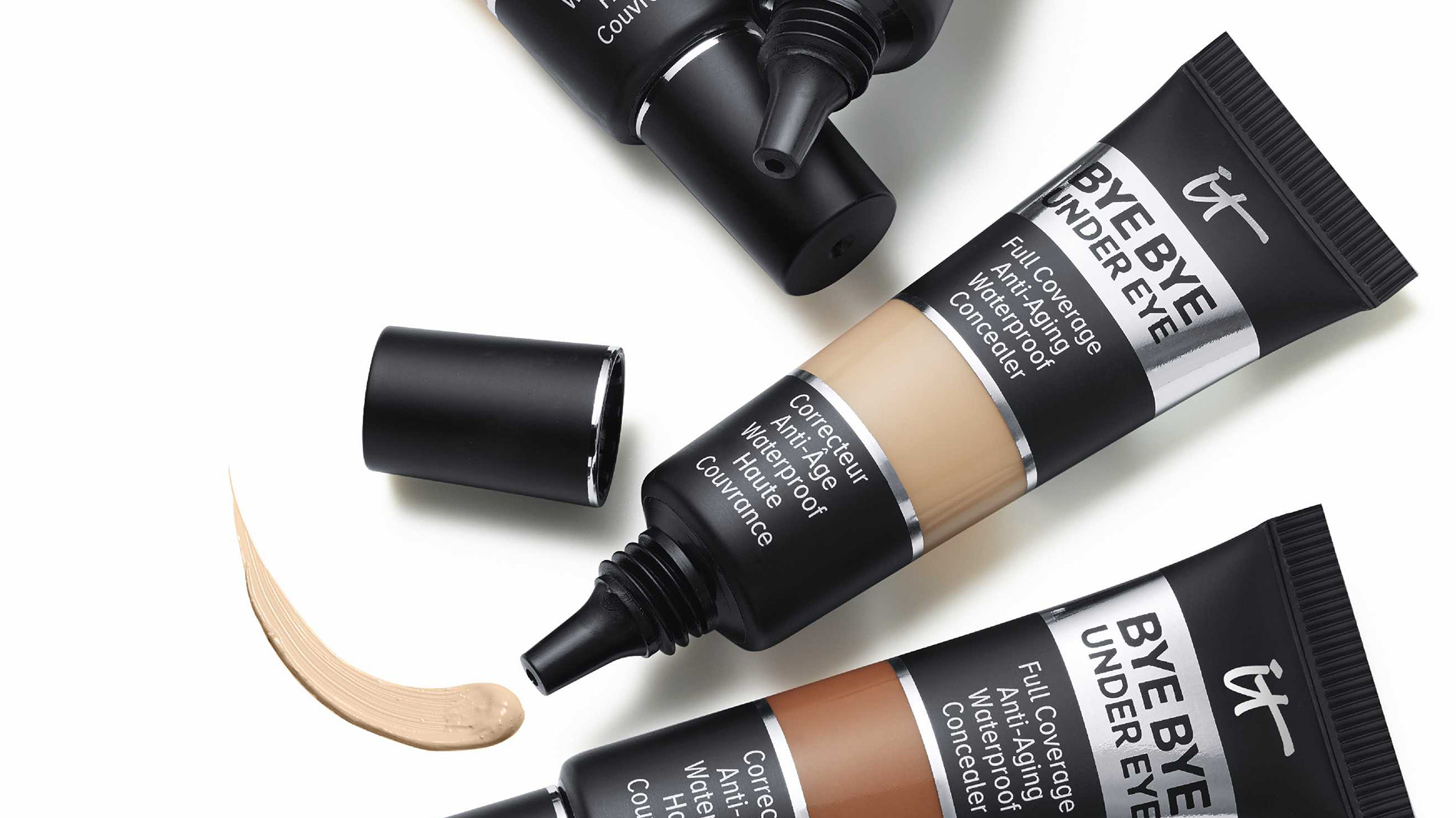 Fire concealere fra merket It Cosmetic i fire forskjellige nyanser mot en hvit bakgrunn.