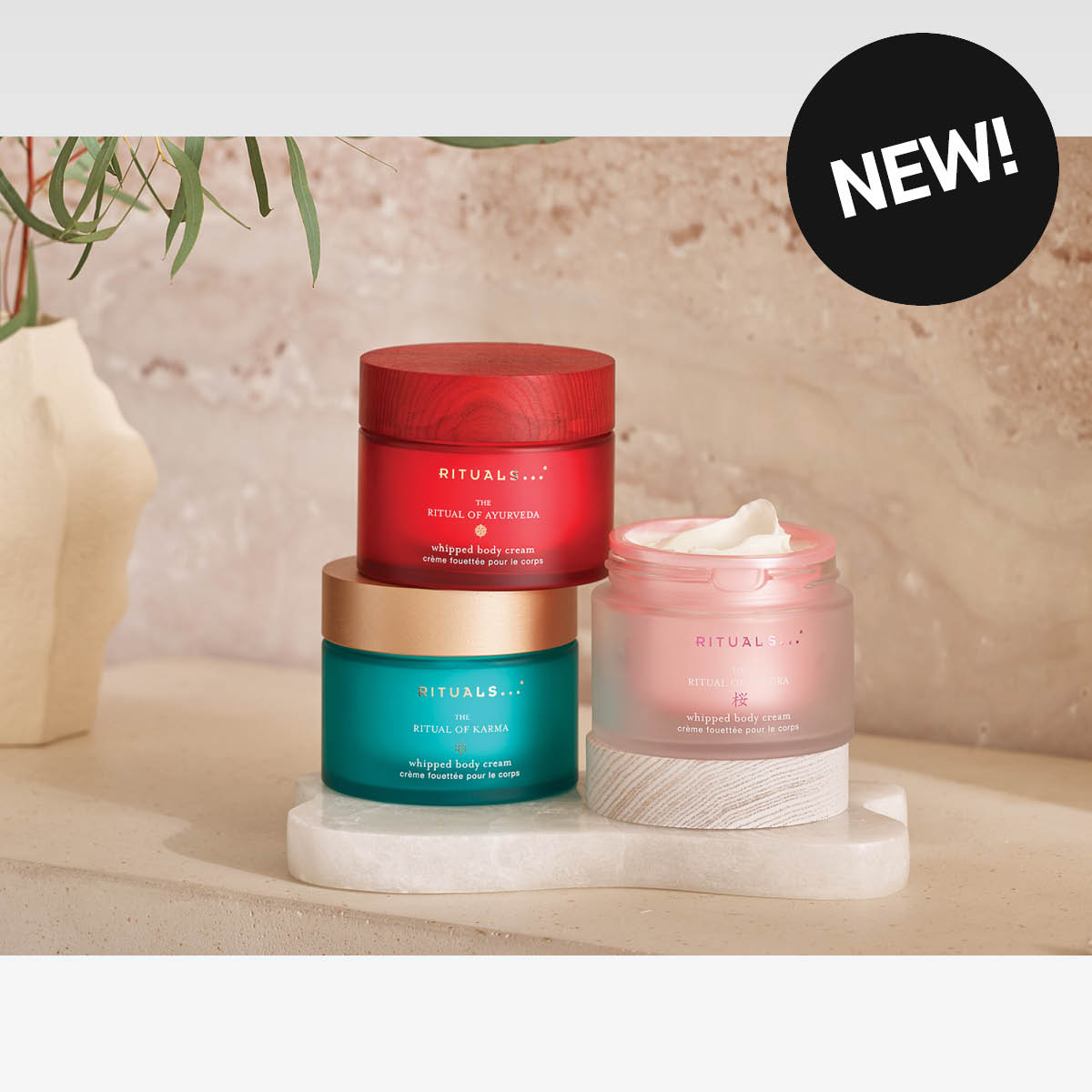 Kolme Rituals Whipped Body Cream -voidetta seisoo kylpyhuoneympäristössä. Tarra, jossa teksti NEW!