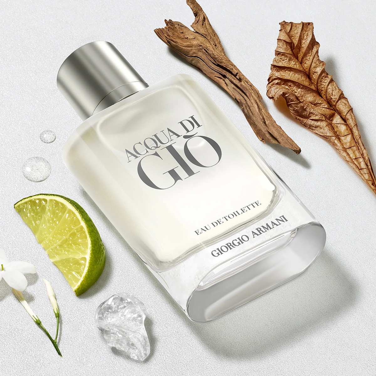 Giorgio Armani Acqua di Giò parfymeflaske på lys bakgrunn med lime, treverk og blomsterdetaljer.