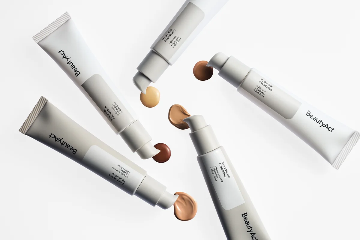 Flera BeautyAct foundationprodukter i vita tuber och pumpförpackningar med foundation i olika nyanser mot vit bakgrund. Synlig text inkluderar ”BeautyAct”, ”Hydra Silk Foundation”, ”+ Glycerin”, ”+ Hydration”, ”+ Soft Glow”, ”Bare Skin Foundation”, ”+ Niacinamide”, ”+ Hydration”, ”+ Satiny Finish”, ”Second Skin Foundation”, ”+ Hyaluronic Acid”, ”+ Hydration”, ”+ Satiny Finish”, ”Hydra Sheer Foundation”, ”+ Hyaluronic Acid”, ”+ Hydration” och ”+ Satiny Finish”.