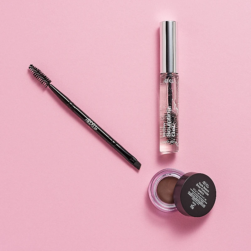 Bilde av tre øyenbrynsprodukter fra Ardell, inkludert en øyenbrynsblyant med børste, Brow Sculpting Gel og Brow Pomade. Produktene er plassert på en rosa bakgrunn.