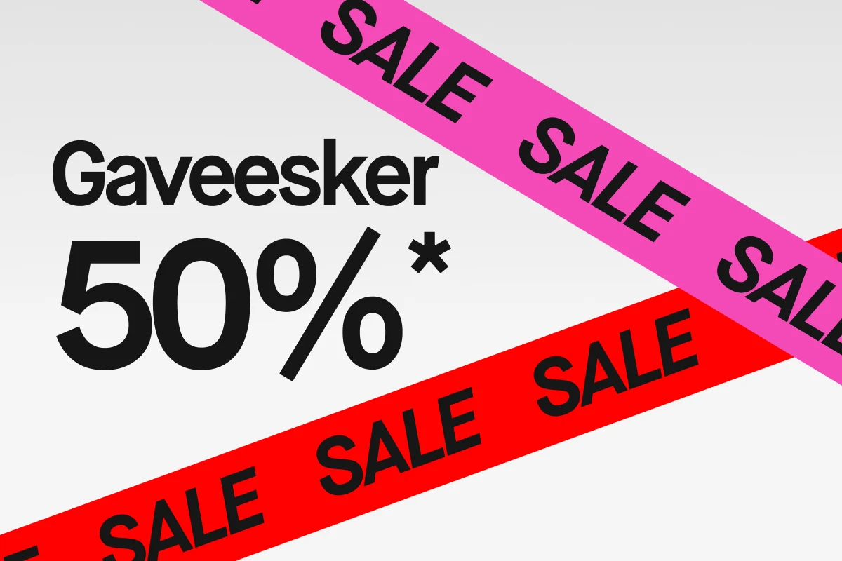 Grafisk bilde med hvit bakgrunn og stor svart tekst «Julaskar 50%*». To diagonale bånd krysser bildet: ett rosa og ett rødt bånd med gjentatt svart tekst «SALE».