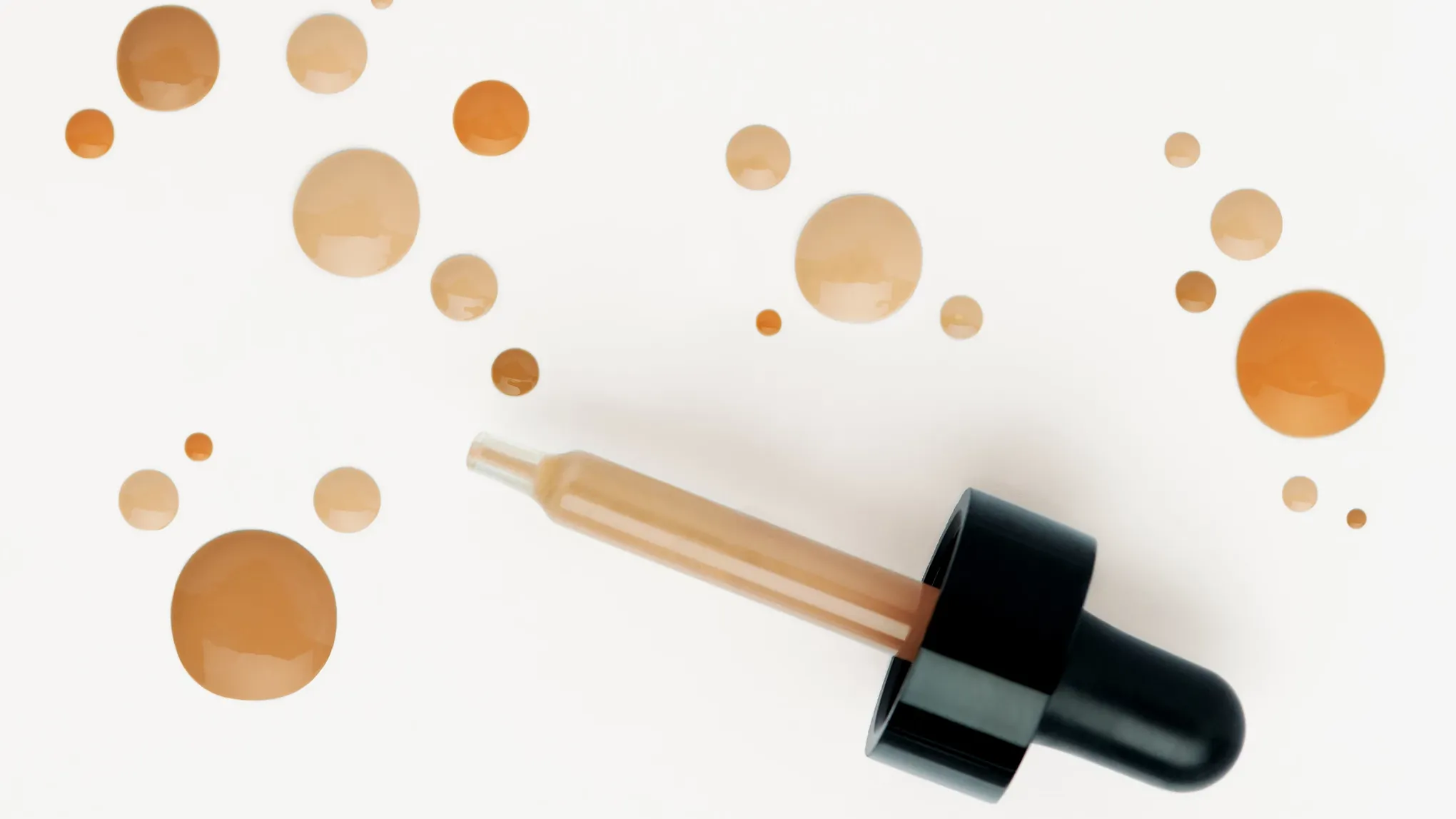 En pipett med bb cream och flera droppar av produkten på en vit bakgrund.