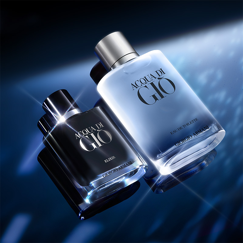 To Acqua di Giò Giorgio Armani-parfymeflasker, en svart og en lyseblå, plassert på en blå overflate. Bakgrunnen har blå belysning.