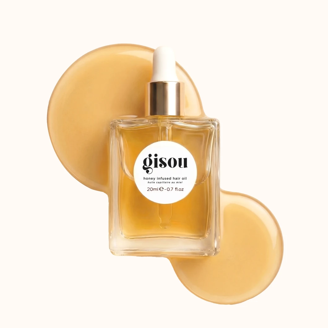 Gisou Honey Infused Hair Oil-flaska, 20ml e-0.7 fl.oz, med spilld gyllene olja.