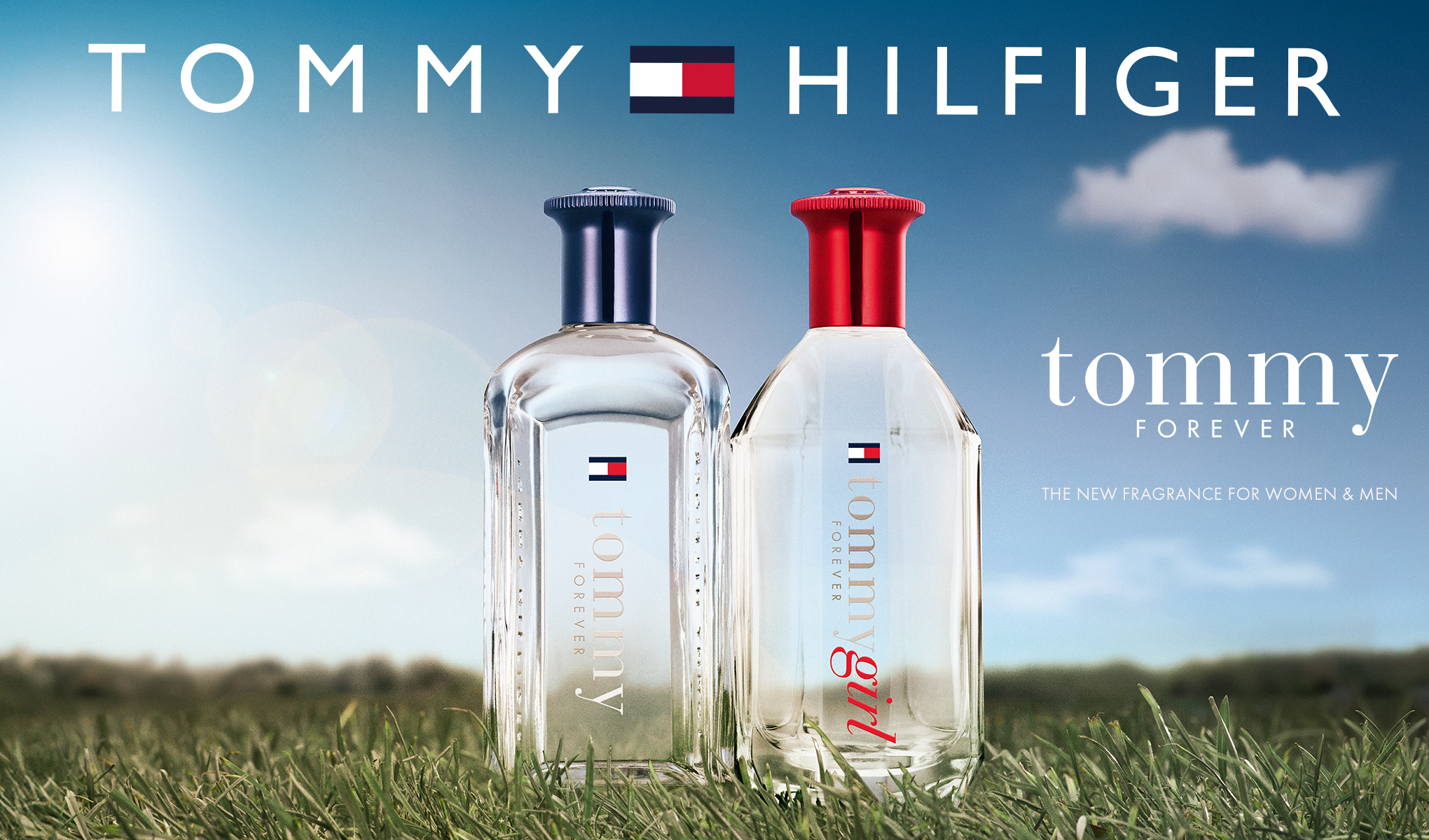 To parfymeflasker fra Tommy Hilfiger står på en gressplen under en klarblå himmel. Øverst står teksten «Tommy Hilfiger» med merkets logo. Nederst til høyre står ordene «Tommy Forever» og «The new fragrance for women & men».