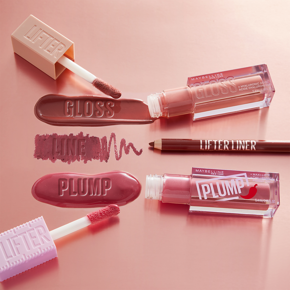 Useita Maybellinen huulituotteita vaaleanpunaisella pohjalla. Tuotteet on avattu, ja niissä näkyy applikaattorit ja värit.