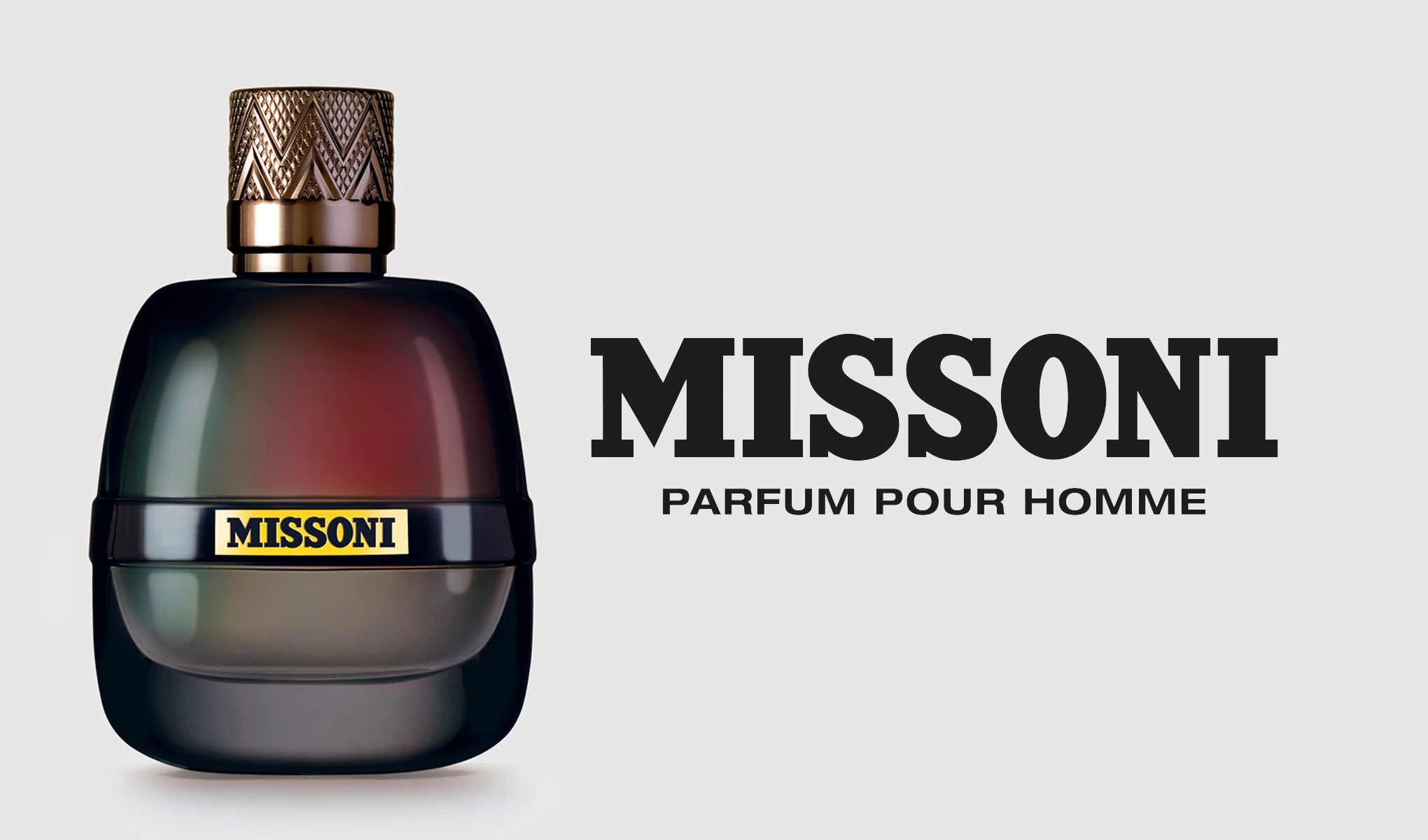 Parfymflaska från Missoni med namnet "Parfum Pour Homme". Flaskan har en mörk gradient färg med inslag av grönt, rött och guld, och en dekorativ kork. Texten på bilden lyder "Missoni Parfum Pour Homme" och bakgrunden är ljusgrå.