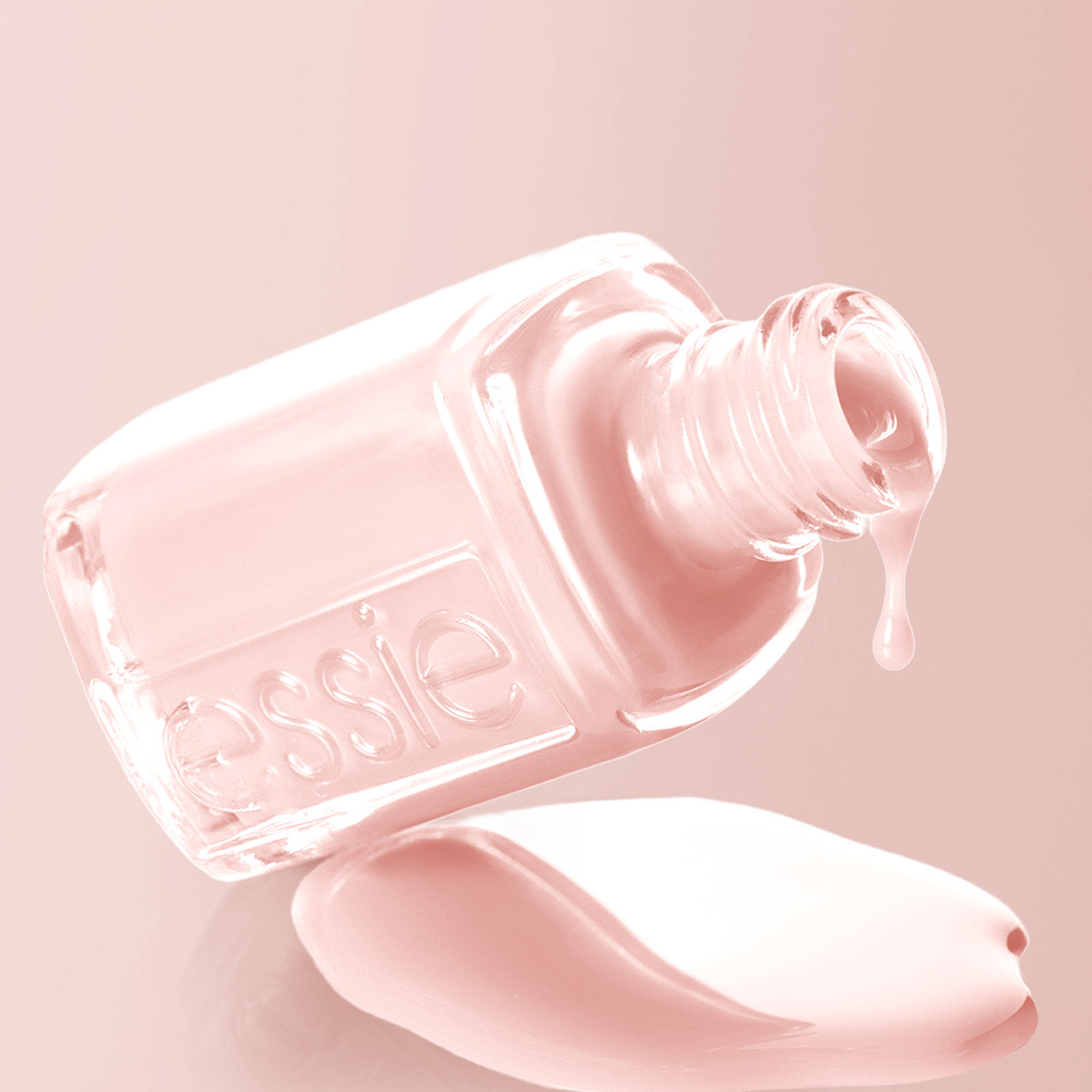 Ljusrosa Essie-nagellack liggande på sidan; lack rinner ut och bildar en pöl under flaskan.
