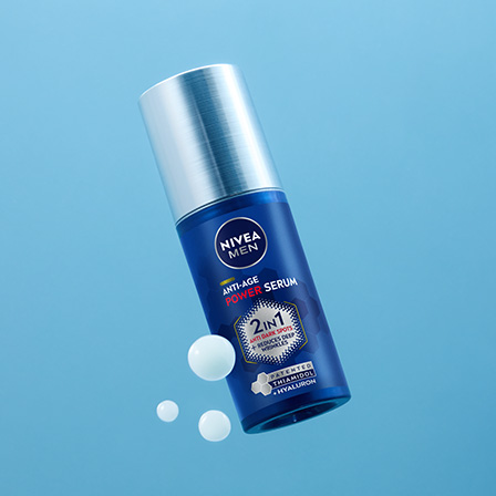 Sininen Nivea-pullo vaaleansinistä taustaa vasten. Pullossa on hopeanvärinen pumppu ja etiketissä teksti ”2in1 Intensive Serum”. Pullon ympärillä on muutamia valkoisia seerumipisaroita, jotka korostavat tuotteen koostumusta.