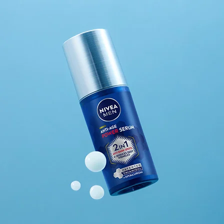 Sininen Nivea-pullo vaaleansinistä taustaa vasten. Pullossa on hopeanvärinen pumppu ja etiketissä teksti ”2in1 Intensive Serum”. Pullon ympärillä on muutamia valkoisia seerumipisaroita, jotka korostavat tuotteen koostumusta.