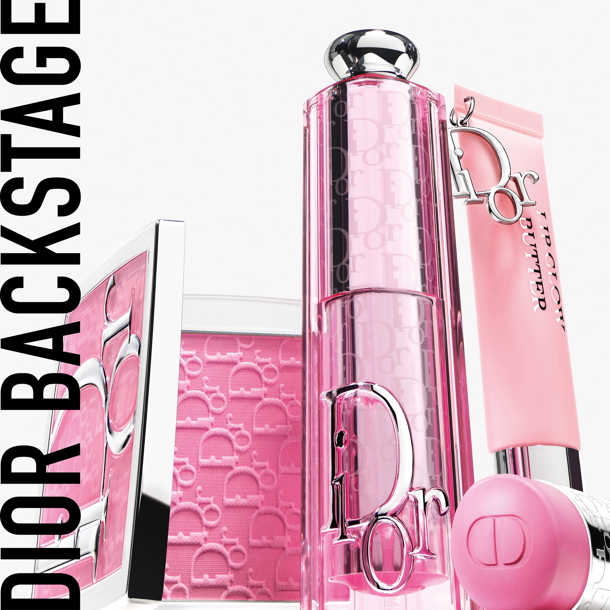 Dior Backstage -meikkituotteet vaaleanpunaisissa sävyissä, mukaan lukien huulivoide, huulipuna ja poskipuna. Tuotteet ovat tyylikkäästi esillä ja korostavat brändin logoa.
