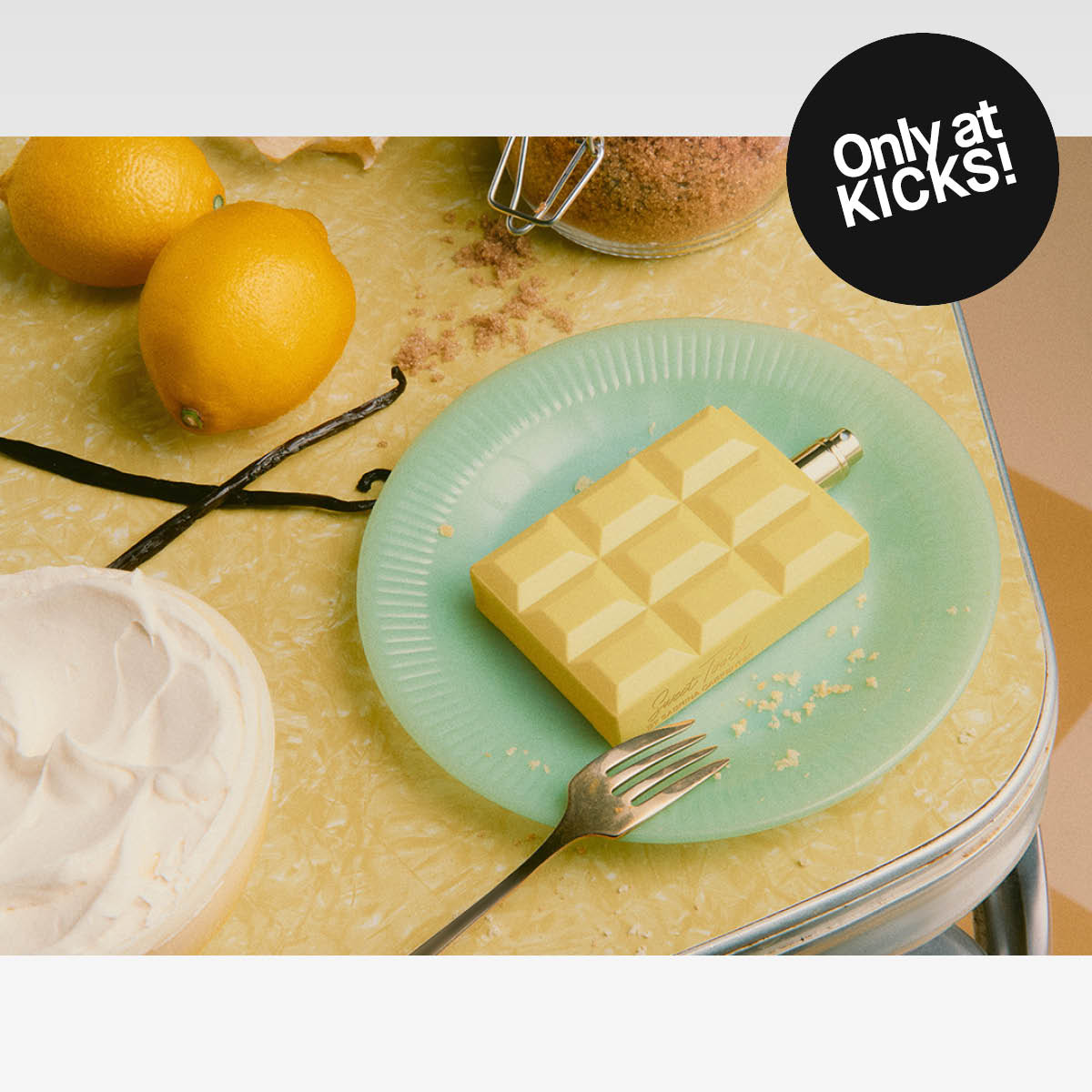 Marknadsbild av Sabrina Carpenter-parfym. Flaskan ligger på en tallrik bland bakverk och citroner, med texten ”Only at KICKS!”.