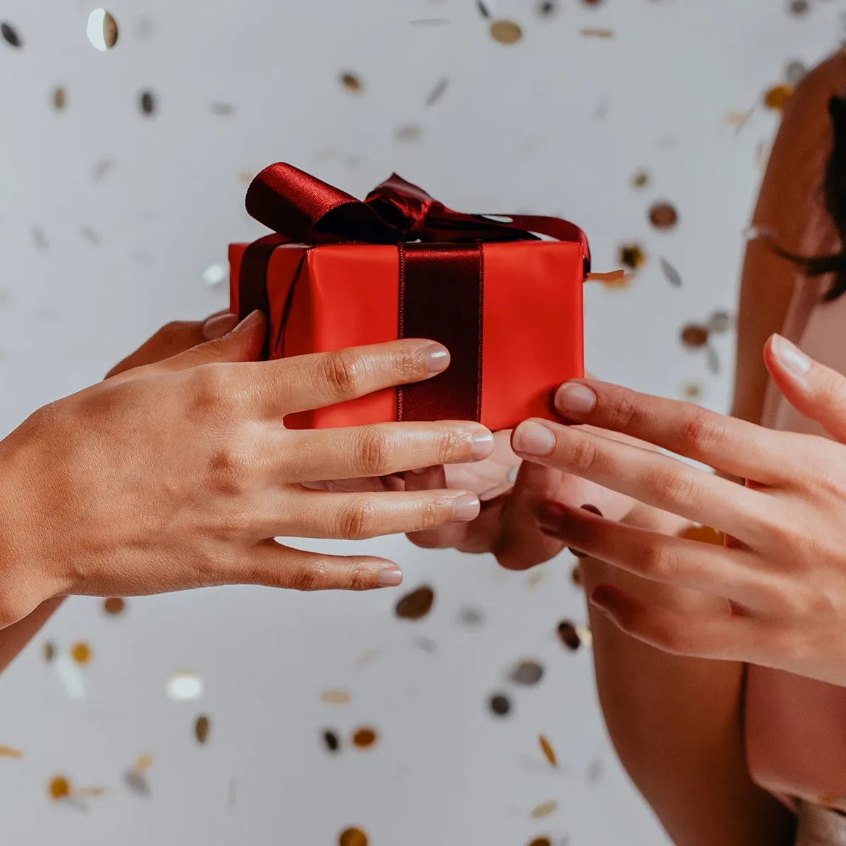 To personer holder en rød gaveeske med et rødt bånd.