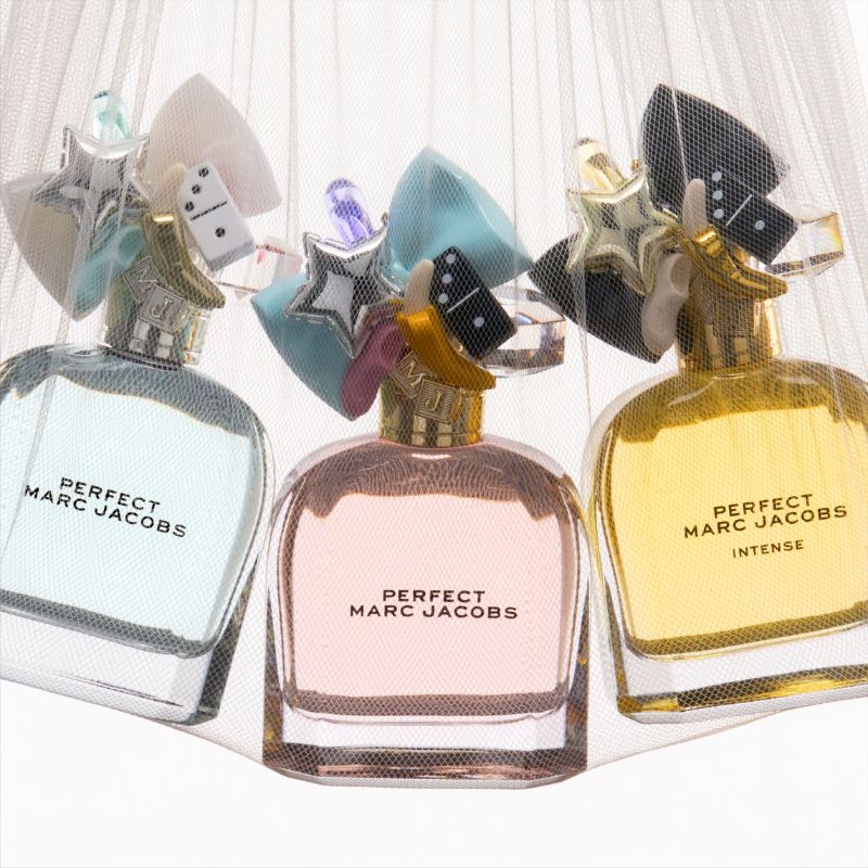 Kolme Marc Jacobsin hajuvesipulloa, joissa jokaisessa on merkintä ”Perfect Marc Jacobs” ja kolmannessa merkintä ”Intense”. Pullot ovat erivärisiä: vaaleansinisiä, vaaleanpunaisia ja keltaisia. Niissä on koristeelliset korkit, joissa on värikkäitä ja kiiltäviä muotoja, kuten tähtiä, noppia ja banaaneja. Pullot on osittain peitetty ohuella valkoisella verkolla.